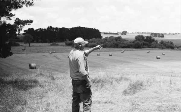 A farmer standing on a field, pointing off-screen.